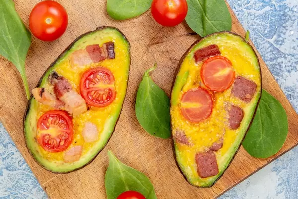 Flat lay above Baked Avocado with Eggs Cherry Tomato and Sausages