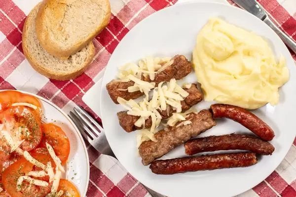 Flat lay above Kebabs Sausages Mashed Potatoes and Tomatoes