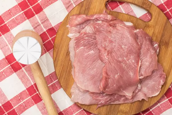 Flat lay above raw Pork Meat and wooden hammer