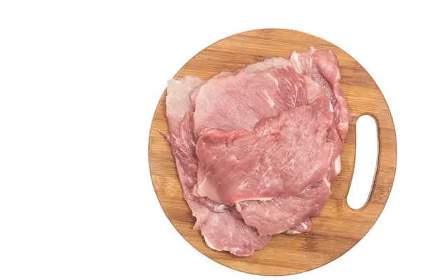 Flat lay above Raw Pork Meat on the round wooden board