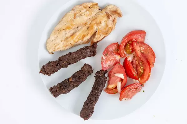 Flat lay above served grilled Chicken Breasts with Kebabs and Tomatoes