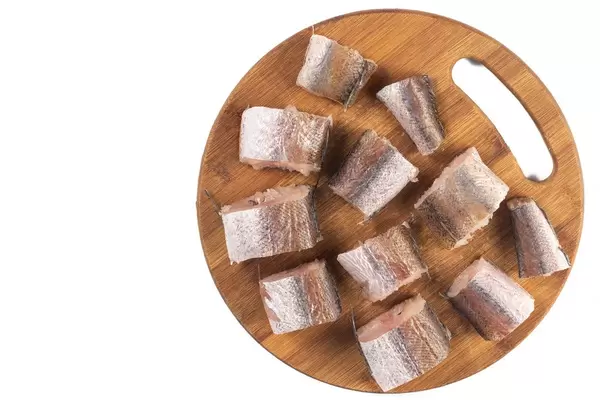 Flat lay above sliced Hake Fish on the wooden board with white copy space