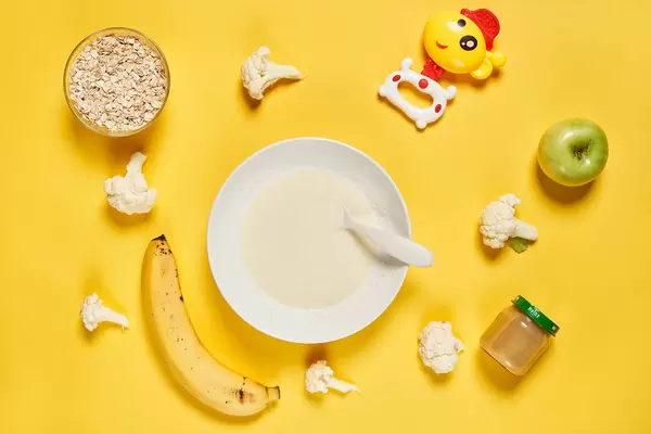 Flat lay composition with bowl of healthy baby food on yellow background