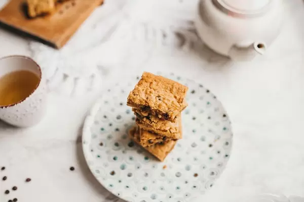 Flat lay of brunch with blonde brownies and tea on white background.