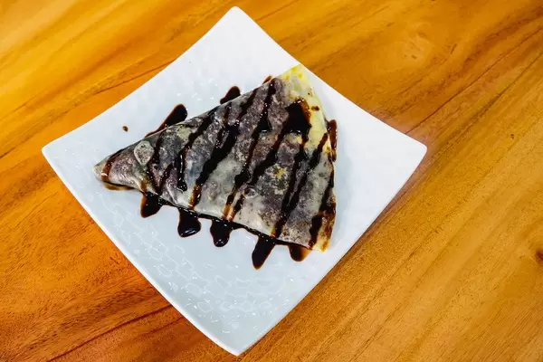 Flat lay of chocolate filled crepe on wooden surface (Flip 2019)