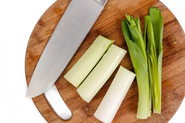 Flat-lay über frisch geschnittenem Lauch mit einem Messer auf einem Holzschneidebrett