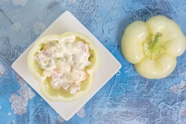 Flatlay einer weißen Paprika mit Füllung, auf einer blauen Tischdecke