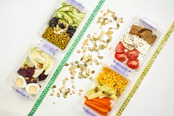 Flatlay image of healthy salads with fresh organic vegetables with measuring tapes on white