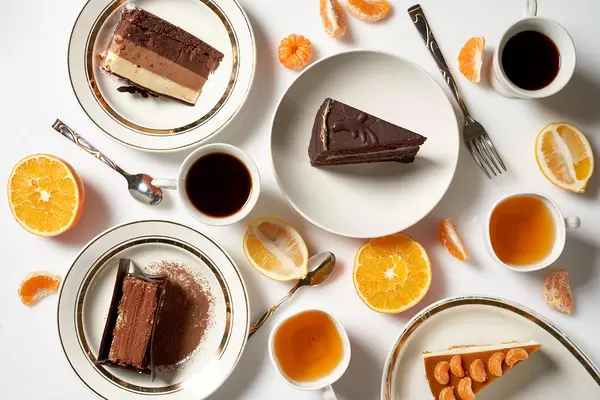 Flatlay: leckere Kaffee- und Teepause mit einem Tortenstück und vielen Zitrusfrüchten