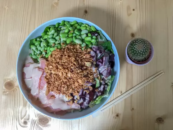 Flatlay of the Salmon Bowl in Simons Stub'n restaurant with salmon, beetroot, edamame, fried onions and soy sesame sauce with chopsticks and a little cactus next to it