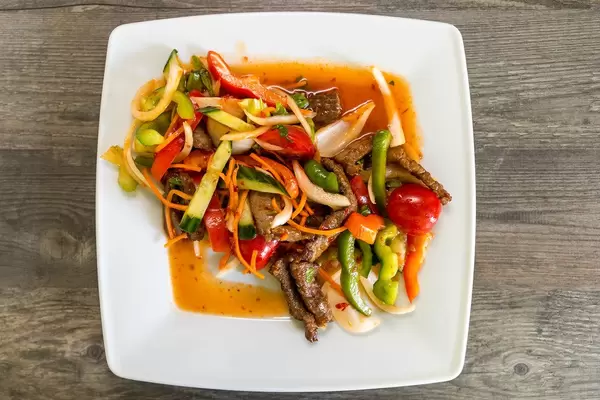 Flatlay shows balanced Thai food with beef, vegetables, carrots, chili, lemon juice, onions, coriander and celery and fish sauce.