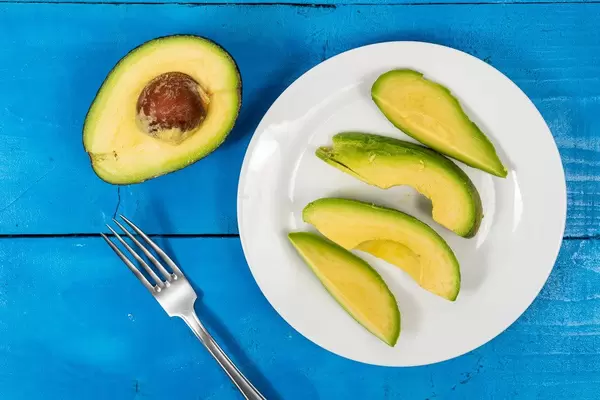 Flatlay von geschnittenen Avocadohälften auf einem blauen Tisch