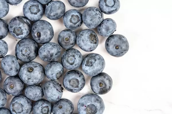 Flatlay von Heidelbeeren neben weißer Fläche