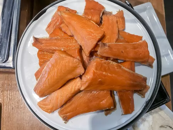 Flatlay zeigt Räucherlacks, portioniert in Stücken geschnitten, liegt auf einem weißen Teller