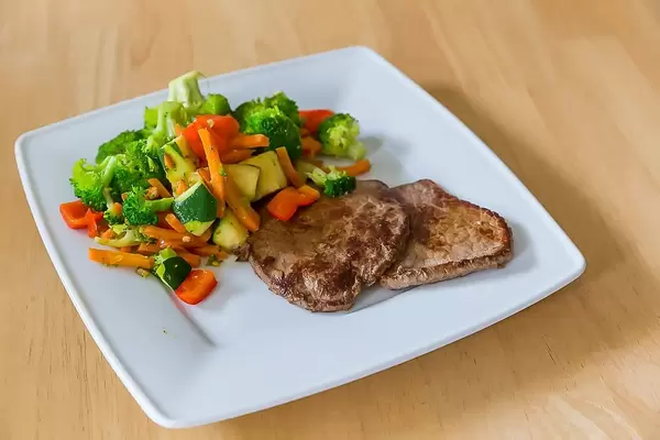 Fleisch mit bunten Beilagen wie Brokkoli und Möhren