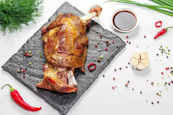 Fleisch mit Knochen gebacken mit Gewürzen und Sauce auf einem weißen Tisch serviert in top view