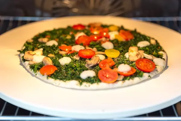 Fleischlose Pizza Verdura der Trattoria Alfredo für Veganer, mit Spinat, Pilzen und gelben Tomaten im Backofen auf dem Pizzastein von BBQ Premium