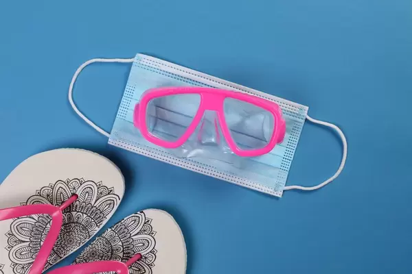Flipflops with medical face mask and diving mask on blue background