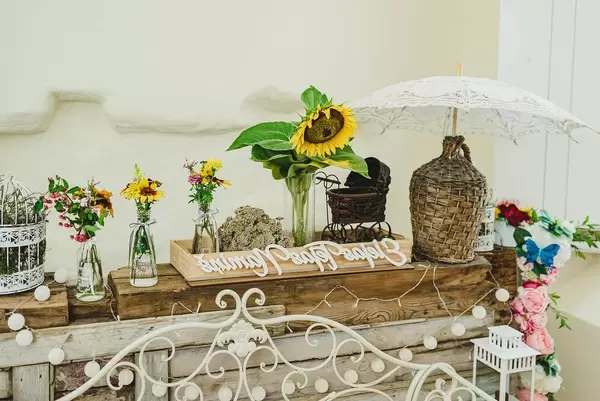 Florale Hochzeitsdekoration auf einem rustikalen Holzregal, mit Sonnenblumen in Vasen