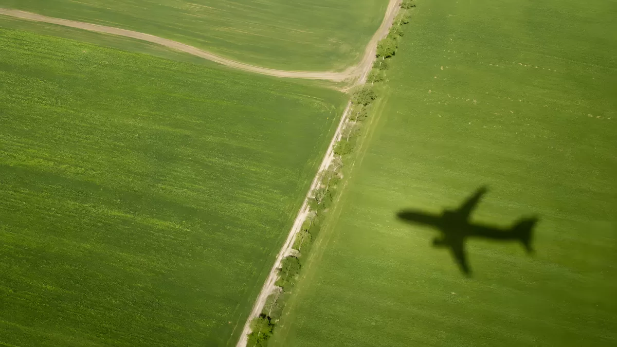 Flugzeugschatten über grünen Feldern aus der Luft