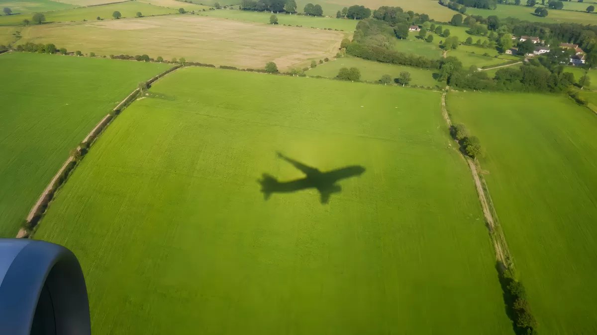 Flugzeugschatten über grüner Landschaft aus der Luft