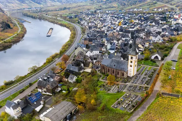 Fluss Mosel und Bundesstraße B49 entlang der Ortsgemeinde Bremm mit St. Laurentius Kirche und einigen Wohngebäuden Luftaufnahme