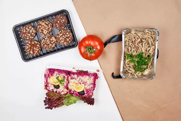 Food bank donations: cookies, a tomato, lettuce, noodles and beetroot dish in one-way packaging