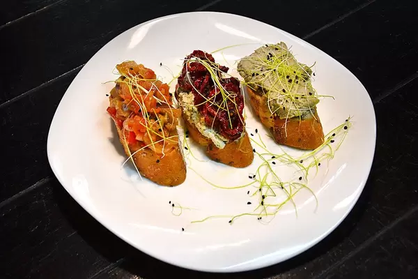 Food Photo of a Starter with Hummus and Vegetable Bruschetta on a White Plate