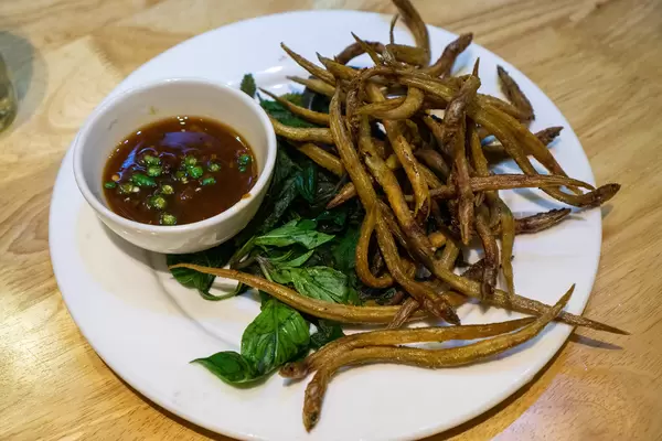 Food Photo of Deep Fried White-spotted Conger Fish on Basil Leaves with Dipping Sauce in a Restaurant