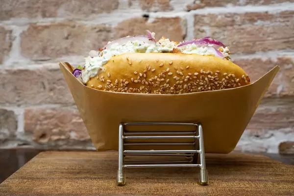 Food Photo of Doner Kebab Sandwich in Fresh Bread with Seasame filled with Red Cabbage, Onions, Lettuce, Meat, Feta Cheese and Tzatziki Sauce