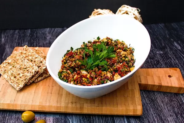 Food Photo of Green Olive Tapenade Paste in White Bowl with Wholemeal Crisp Bread on Wooden Cutting Board
