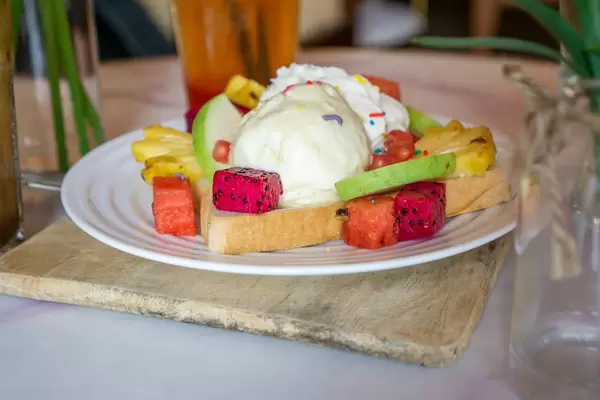 Food Photo of Toast with Vanilla Ice Cream and Fruits such as Dragon Fruit, Pineapple, Watermelon and Guava on a White Plate