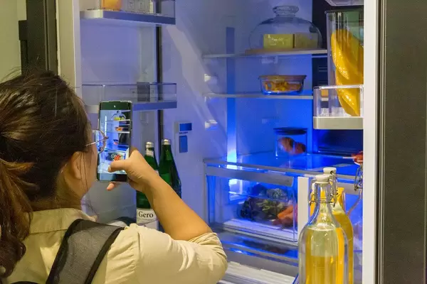 Food Photography: Woman takes a picture of the filled fridge interior