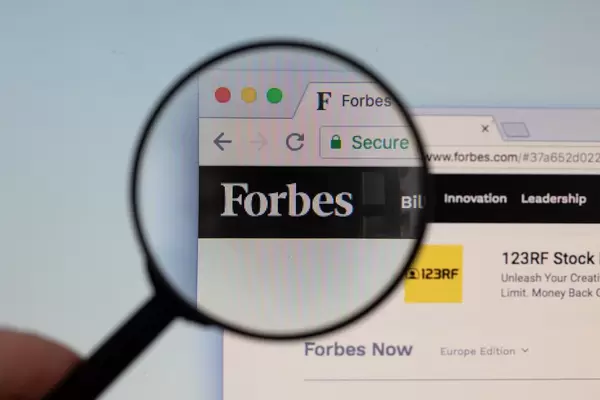 Forbes-Logo am PC-Monitor, durch eine Lupe fotografiert