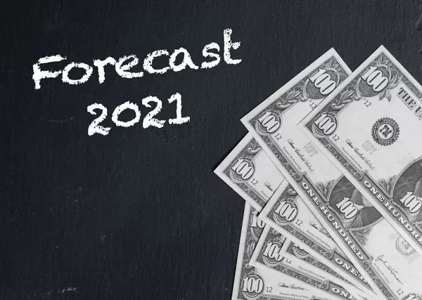 Forecast 2021 text with US dollar banknotes