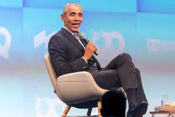 Former Potus Barack Obama sits on a chair and holds a microphone while talking at Bits & Pretzels investors festival, around Oktoberfest in Germany