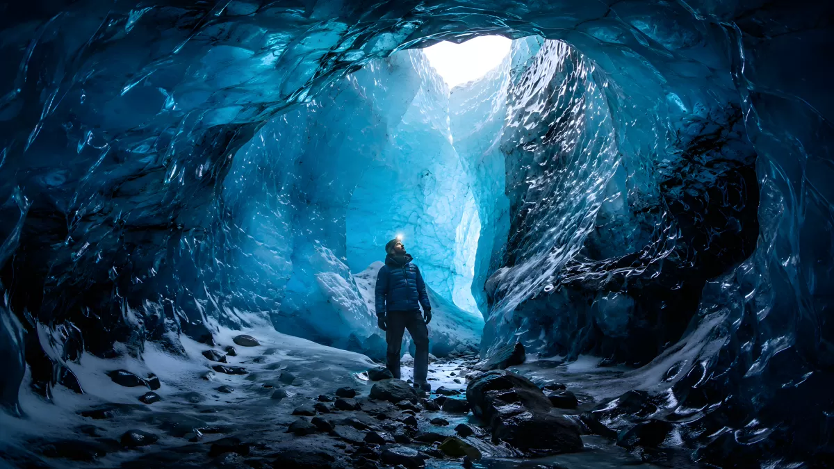 Forscher steht in leuchtend blauer Eishöhle