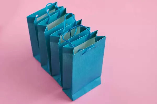 Four blue gift bags on a pink background