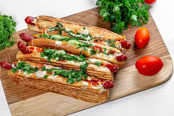 Four hot dogs on the kitchen Board with fresh herbs and tomatoes. Top view (Flip 2019)