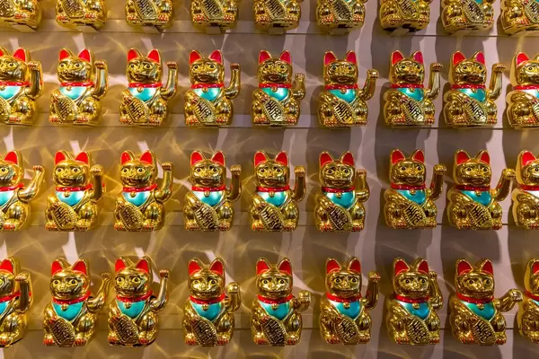 Four rows of Japanese golden beckoning cats as fortune bringers in coa Wok & Bowl restaurant in Cologne