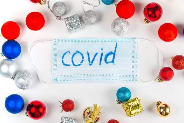 Frame made of Christmas toys and gifts and a medical mask with the inscription covid in the middle