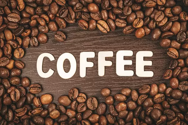 Frame made of coffee beans on brown background with word coffee made from wooden letters