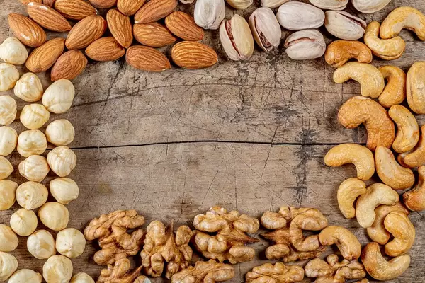 Frame made of different nuts on an old wooden background with free space, top view (Flip 2020)
