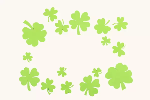 Frame made of paper clover leaves on a white background, top view