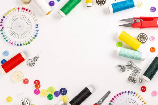 Frame of a variety of accessories and supplies for sewing and repairing clothes on white, top view