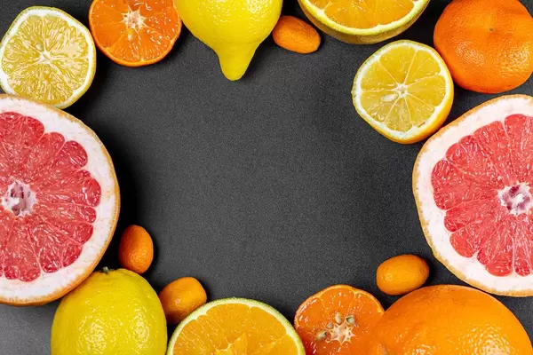 Frame of different citrus fruits on a black background with a free space in the middle