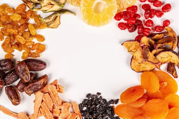 Frame of different dried fruits on white with free space