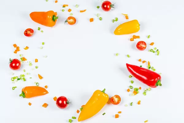 Frame of fresh bell peppers, tomatoes and sliced onions on a white background