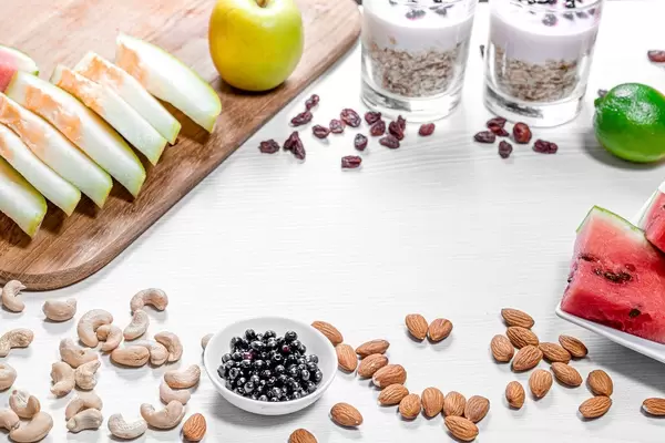 Frame of fruits, oatmeal and nuts for a healthy breakfast on a white wooden background