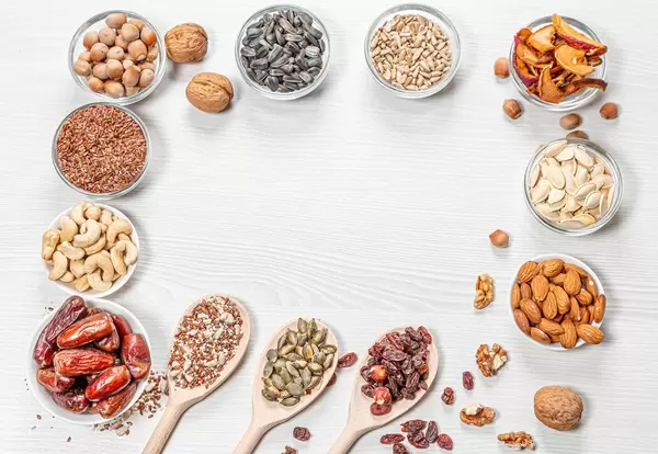 Frame of health food ingredients on white wooden background. Nuts, seeds, dried fruits (Flip 2019)